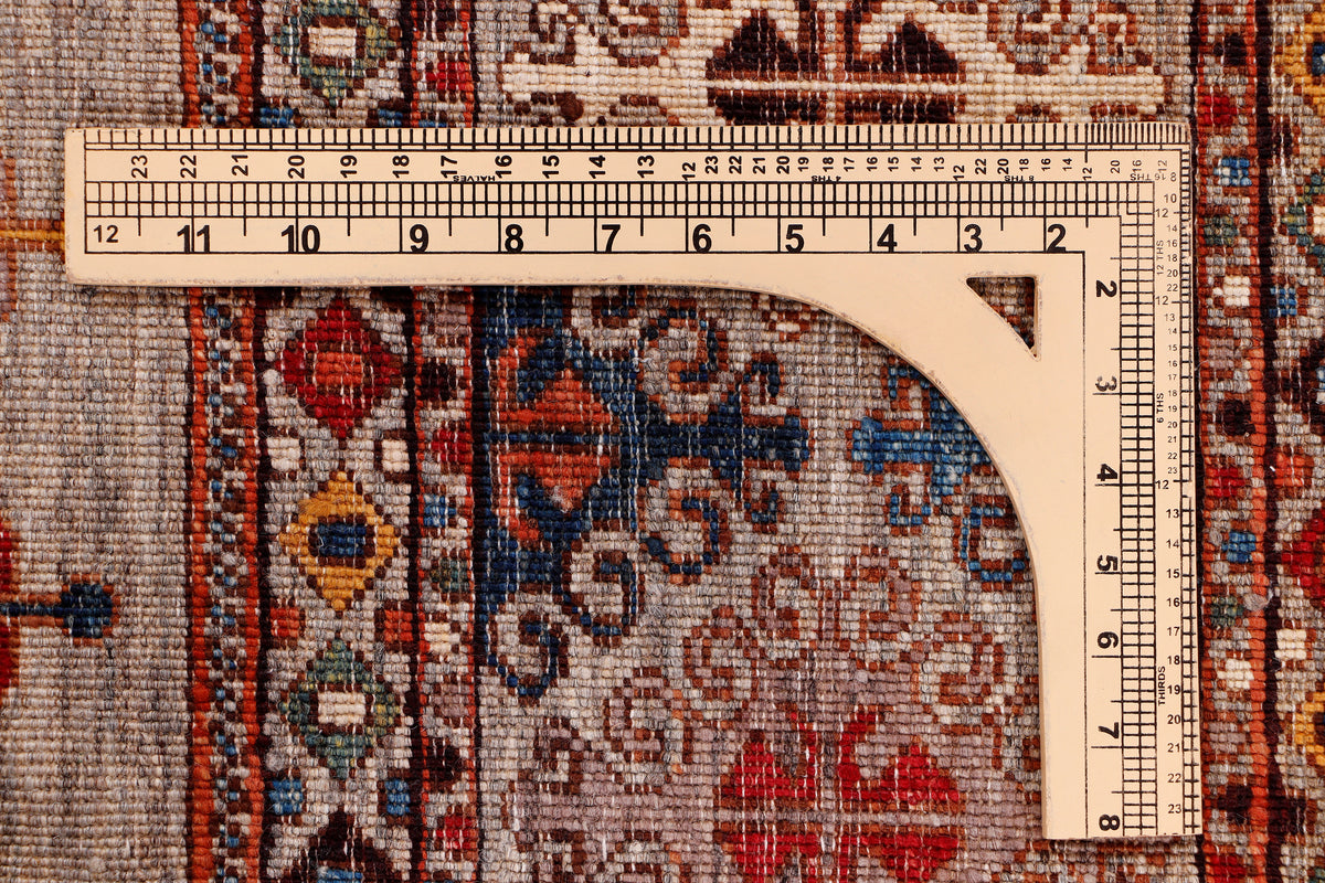 Rug with ornate border and central design; measuring tape laid across the surface.