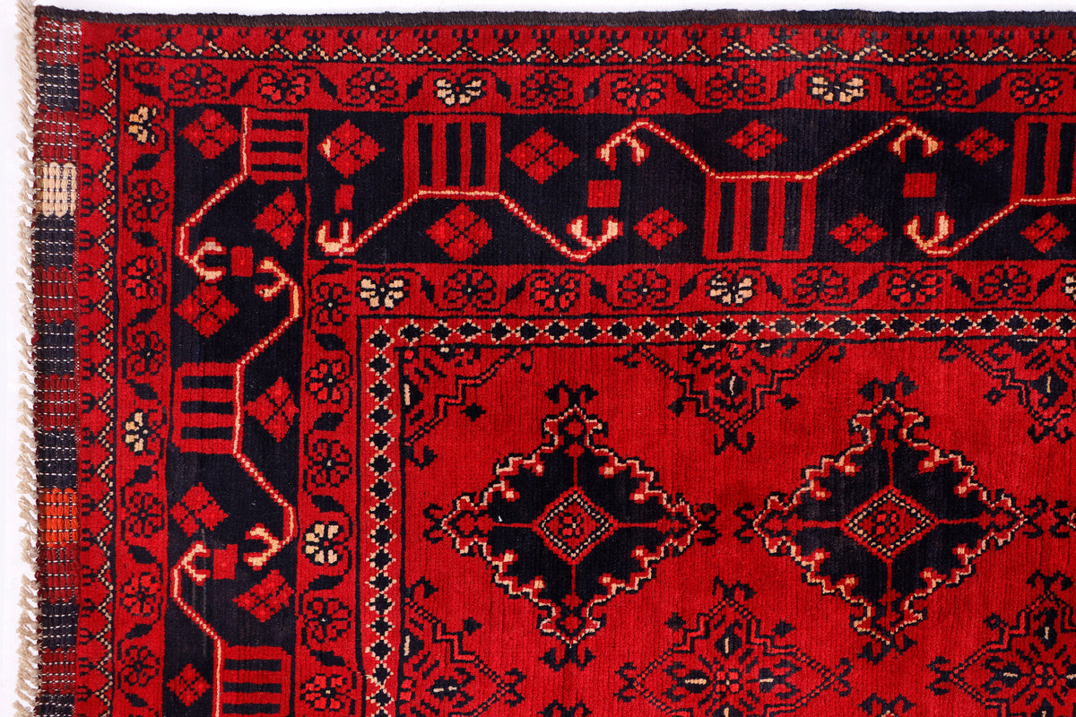 Red rug close-up with central medallions, repeating ornaments, and dark navy accents