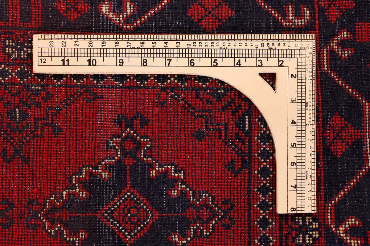 Red rug with ornate geometric border, medallion pattern, and dark black accents