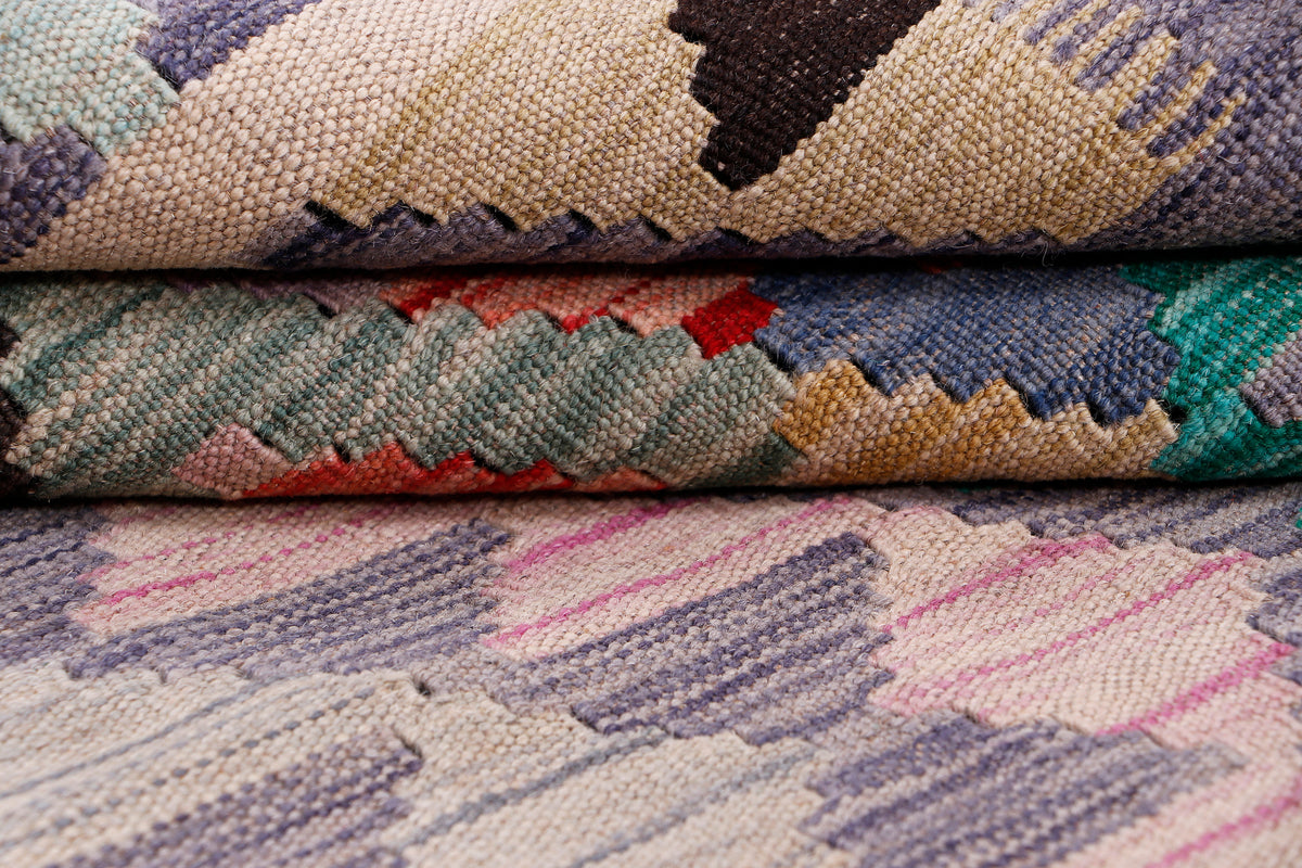Kilim rug close-up showing textured weave and stacked geometric bands in muted colors