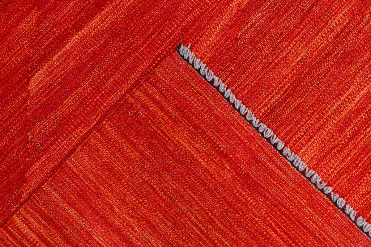 Red rug corner with fringed edge and diagonal woven pattern