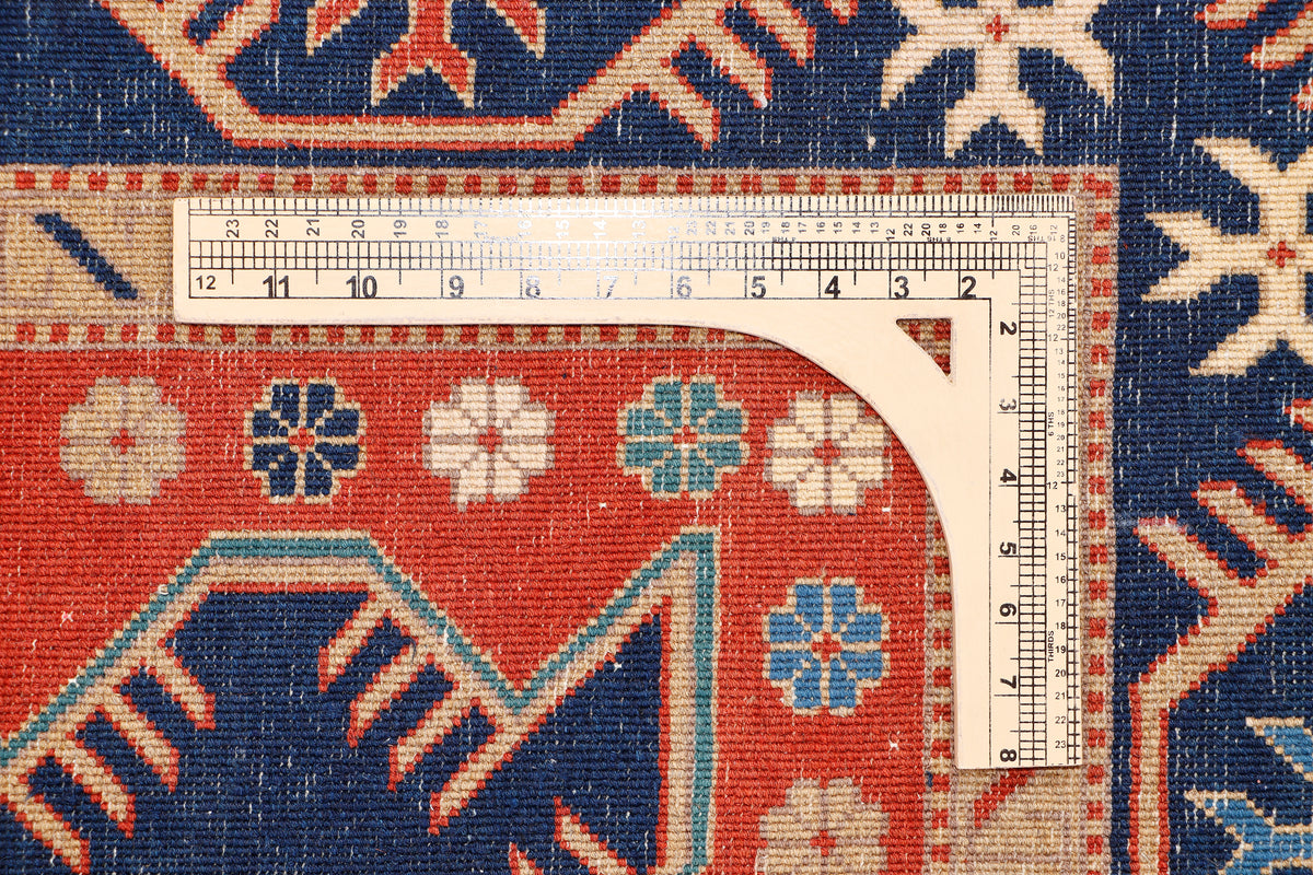 Geometric area rug edge with measurement tape and colorful motifs in blue and red.