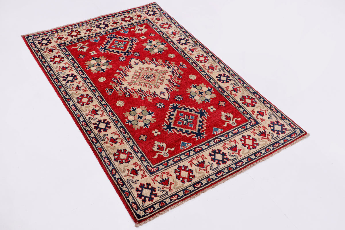 Red area rug with cream medallion and blue trim, ornate geometric motifs, angled view