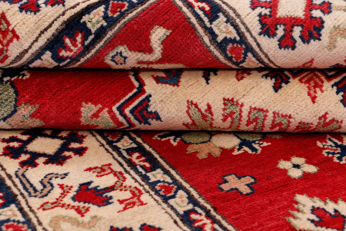 Stacked rug corners showing red field and cream ground with blue geometric outlines