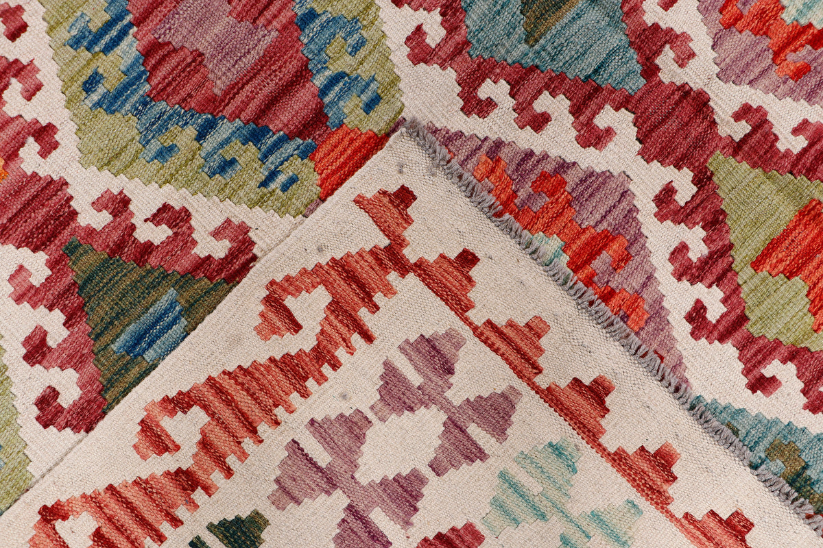 Kilim rug corner with red fringe and multicolor geometric pattern on cream