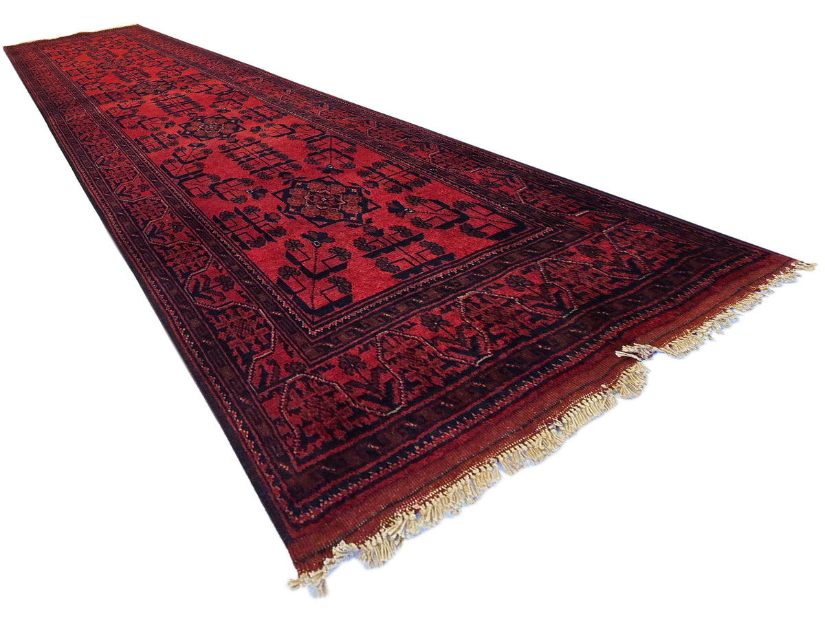 Khanmohamad rug runner in deep red with dark medallion motifs and fringe at corners.