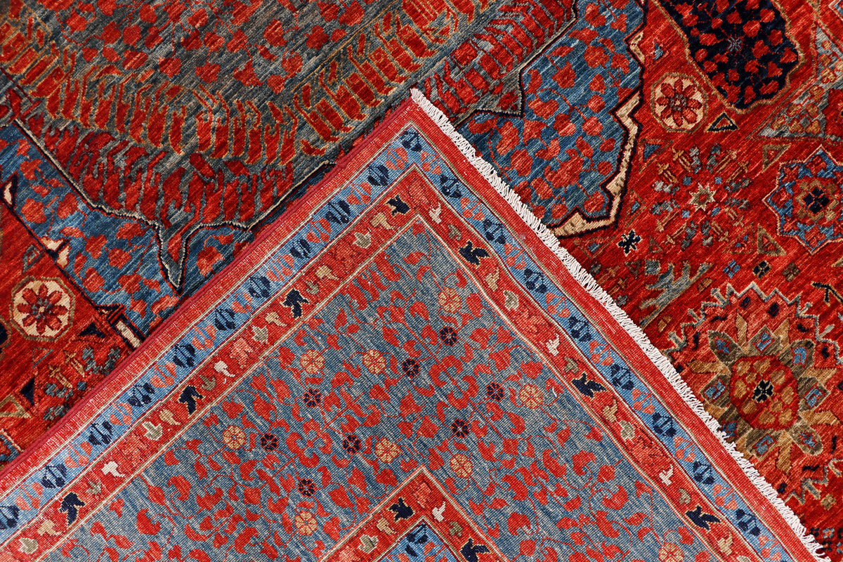 Rug corner detail with blue outer border, red field, and ornate geometric motifs