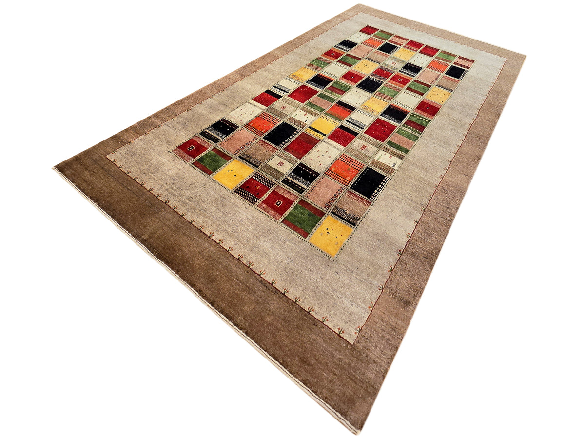 Loribaft rug with colorful patchwork medallion on beige ground, angled view