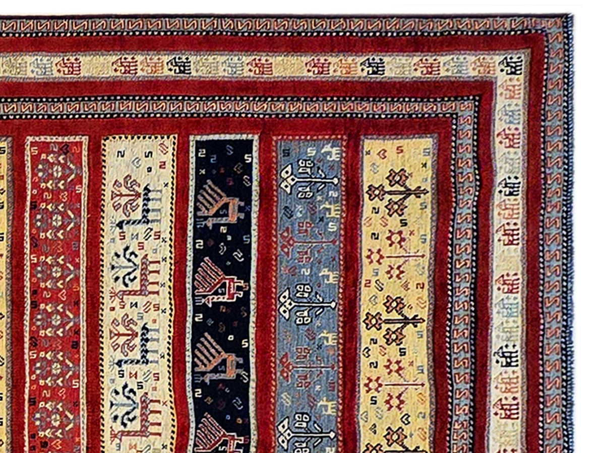 Close-up of rug border with red background, cream panels, blue motifs and geometric trims