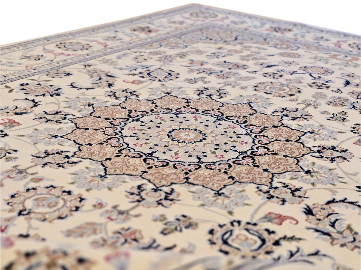 Close-up of cream area rug with blue floral medallion and scrolling vine details.