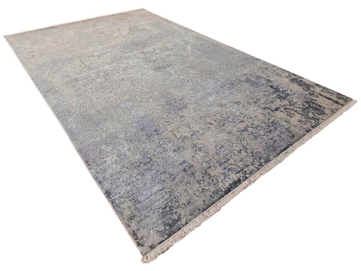 Modern area rug from corner view, faded blue-gray abstract design with fringe