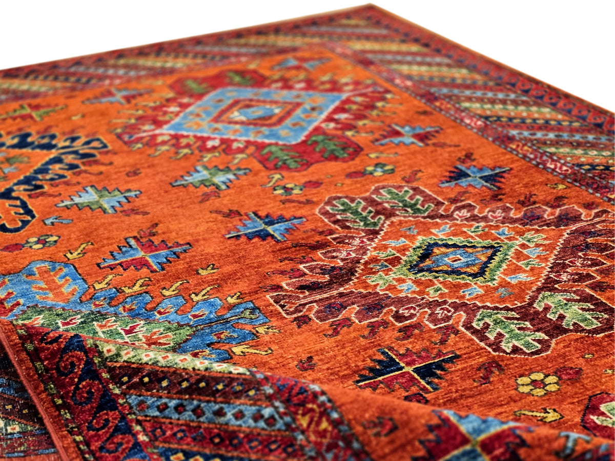 Rug surface close-up with red-orange pile and multicolor geometric motifs in rows