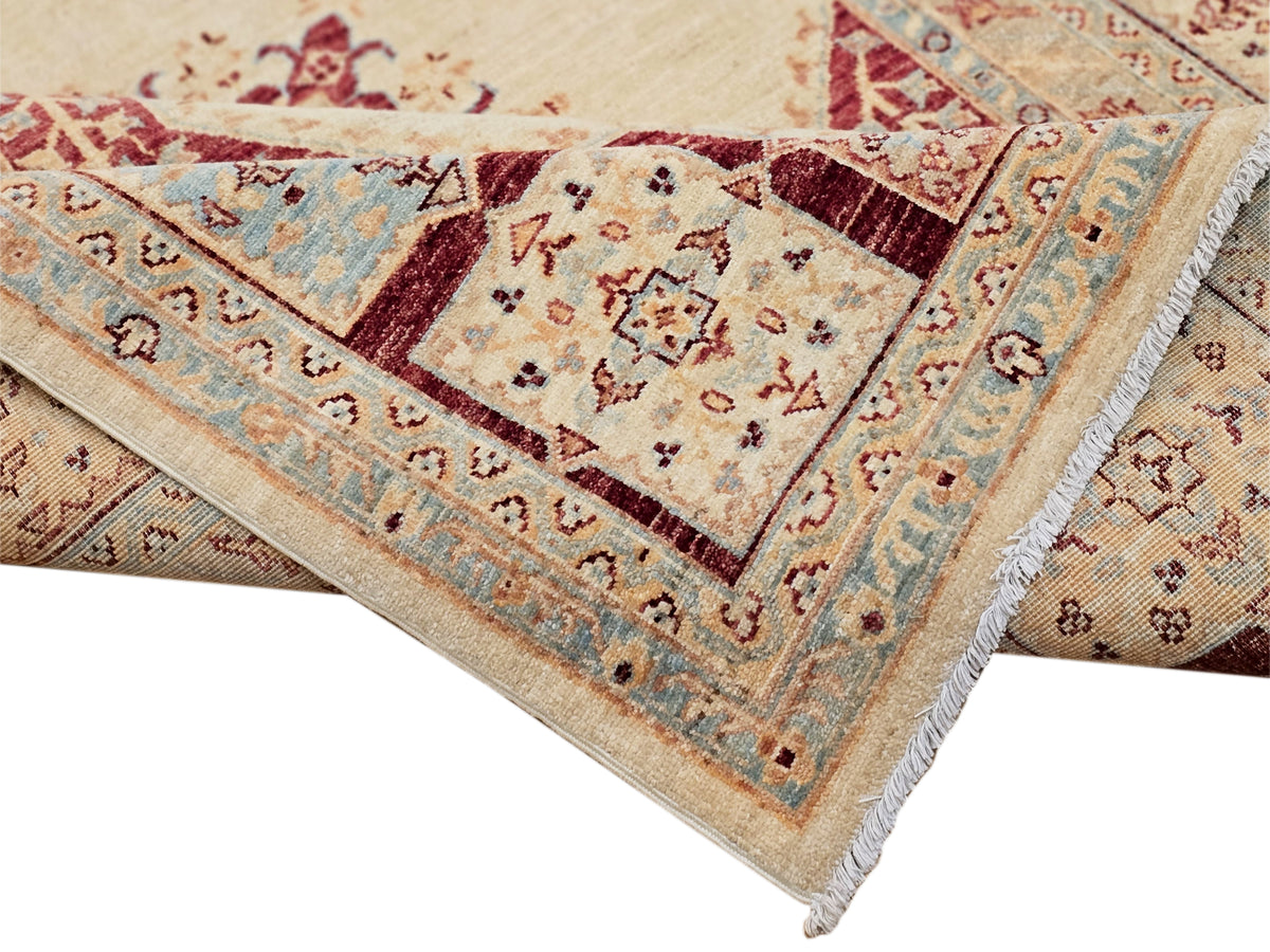 Corner detail of Ariana rug with cream ground, red and blue squares, and fringed edge.