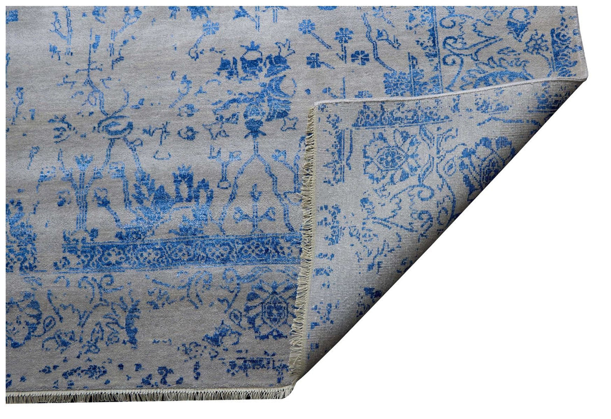 Blue and white patterned rug corner, visible rolled edge and tassel fringe