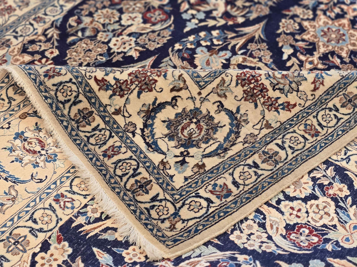 Corner close-up of navy and cream floral rug with geometric border and decorative medallion