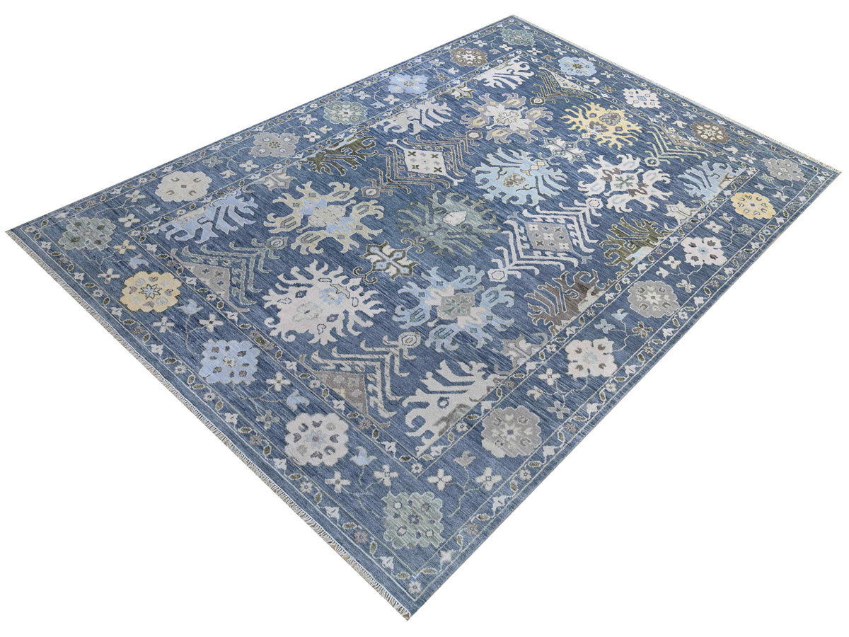 Oushak rug with blue tones and scrolling vine geometric motifs, rectangular flat lay