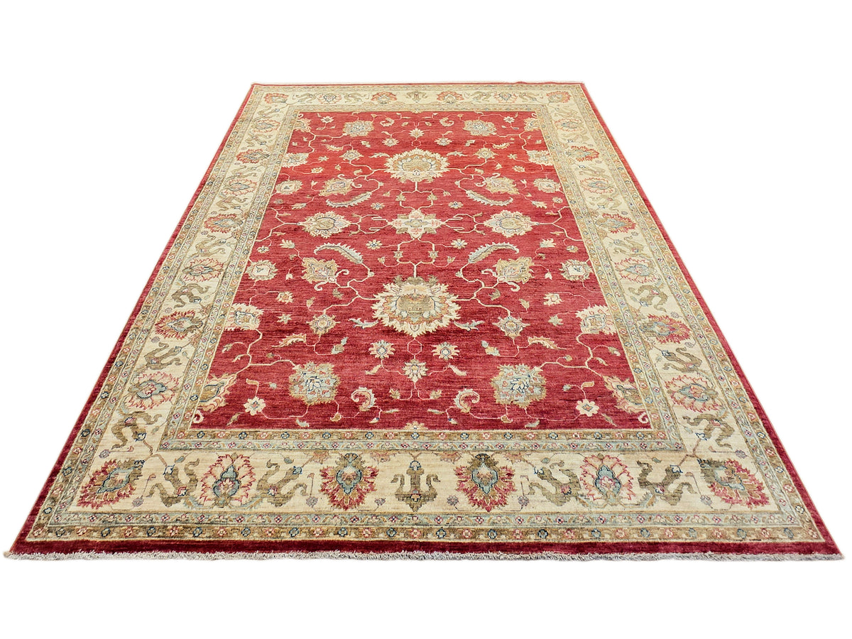 Large red rug with cream ornamental border, central floral medallion, and corner motifs.