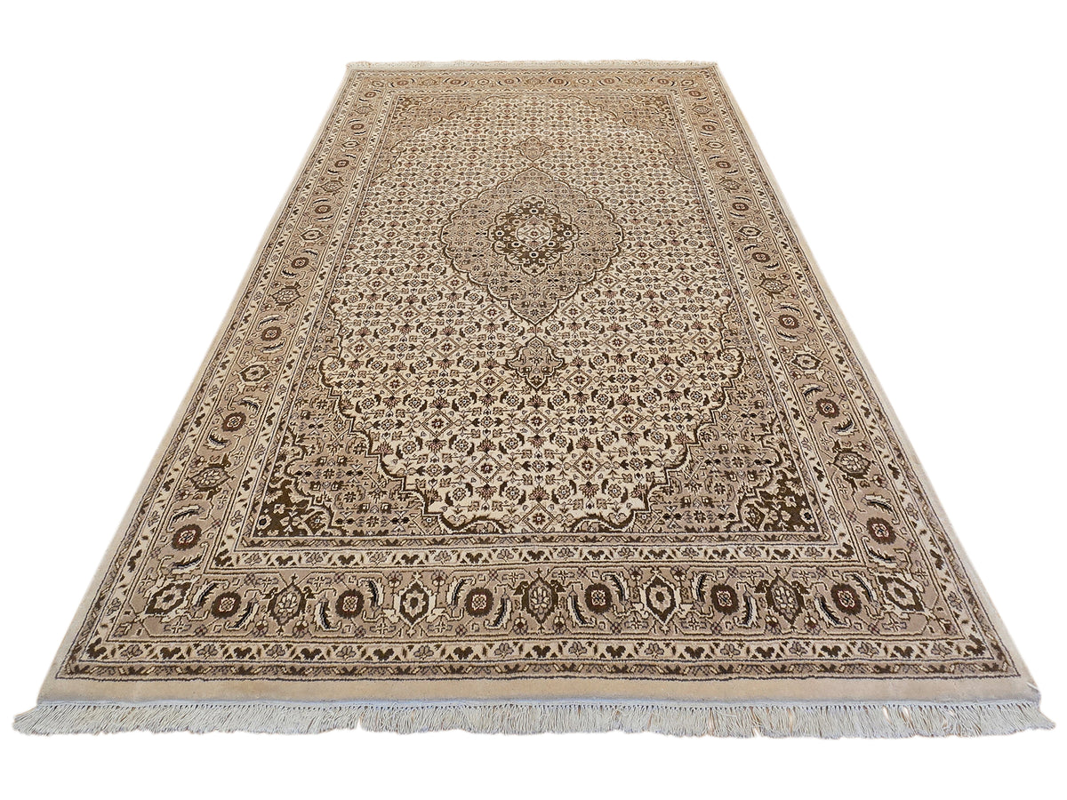 Beige and brown rectangular rug with central floral medallion and ornate frame border.