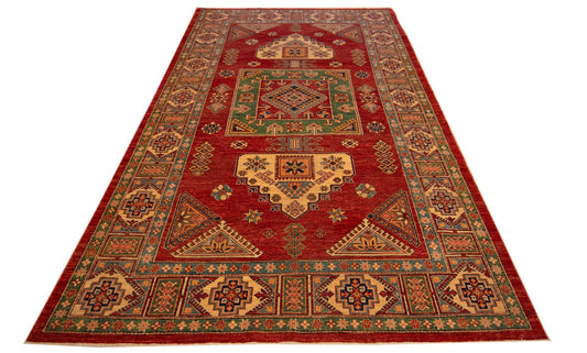 Rectangular red rug with ornate geometric border and central medallion, angled view