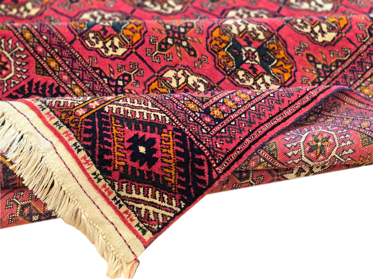 Red rug folded corner with fringed edge and detailed geometric border accents