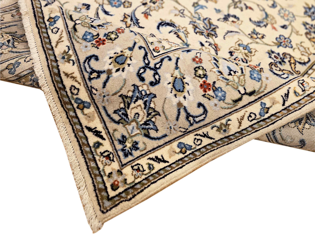 Kashan-style rug corner close-up with blue, cream, and small red accent details