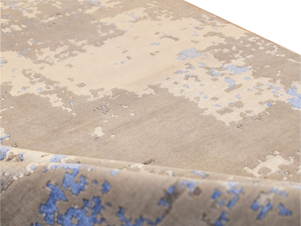 Close-up of rug surface with cream, gray, and blue abstract motif and pile