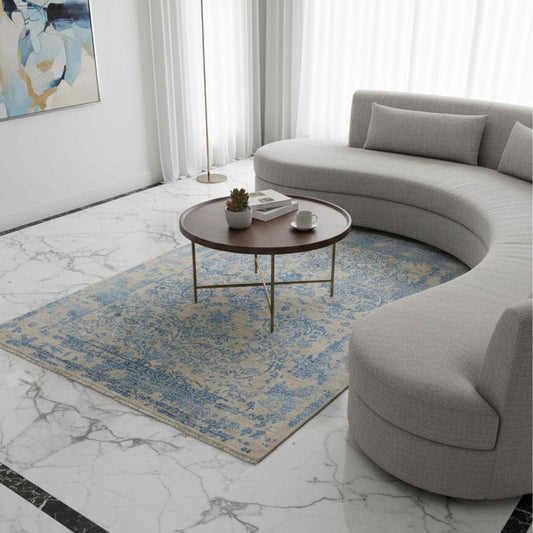 Blue abstract patterned area rug on the floor, light beige field with fringed edge.
