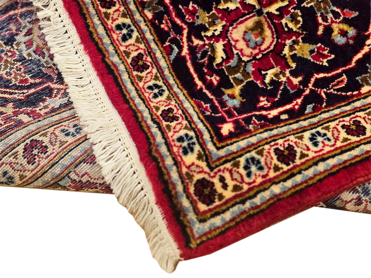 Kashan rug corner with cream fringe, red and navy geometric floral border