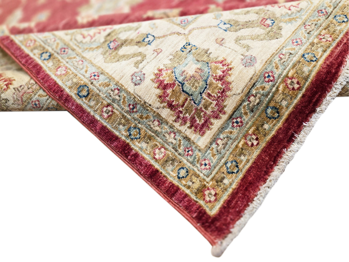 Corner close-up of red and cream rug with detailed small floral motifs and edging.