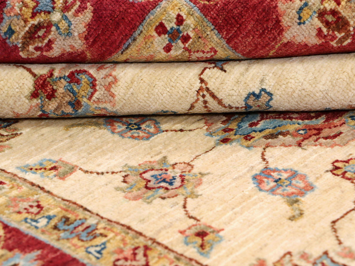 Traditional rug close-up showing cream and red floral motifs with patterned border