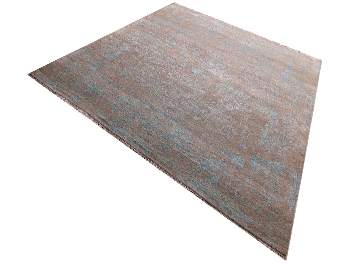 Modern area rug angled view with tan base and muted blue abstract distressed motifs