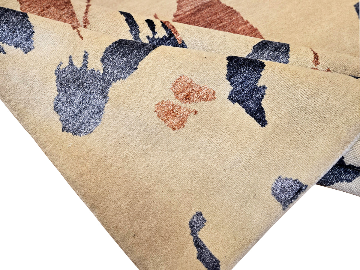 Beige rug corner close-up with blue and rust abstract speckled design