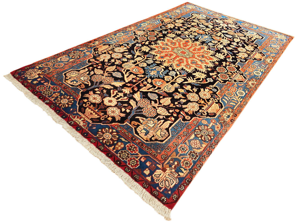 Nahawaand rug corner view with black central medallion, orange/red accents, cream-blue details, fringe.