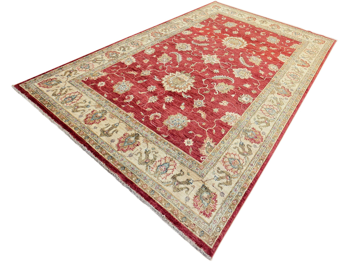 Red rectangular area rug with cream patterning, floral motifs, and ornate border.
