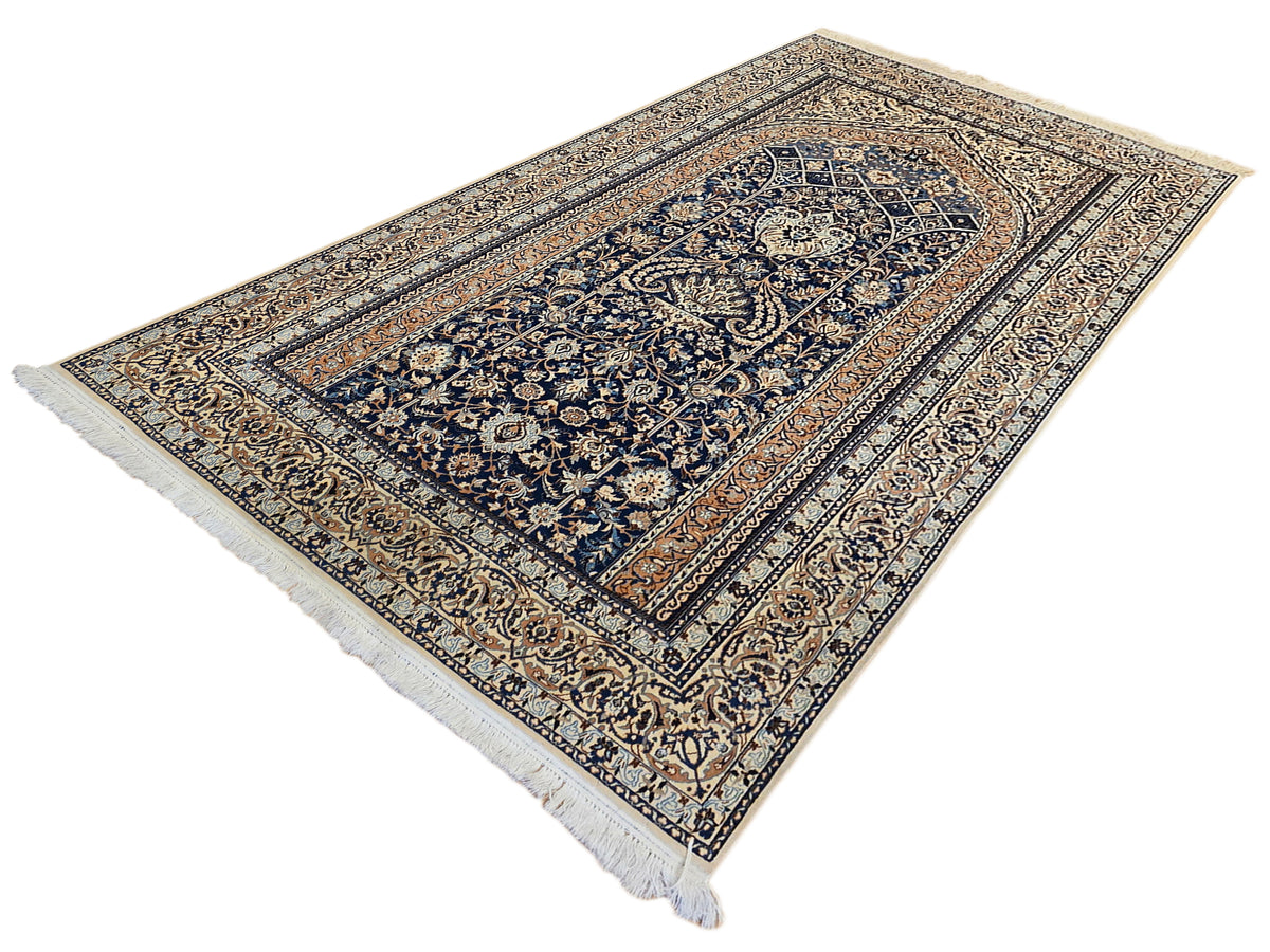 Deep blue and tan ornate area rug with central medallion and fringe