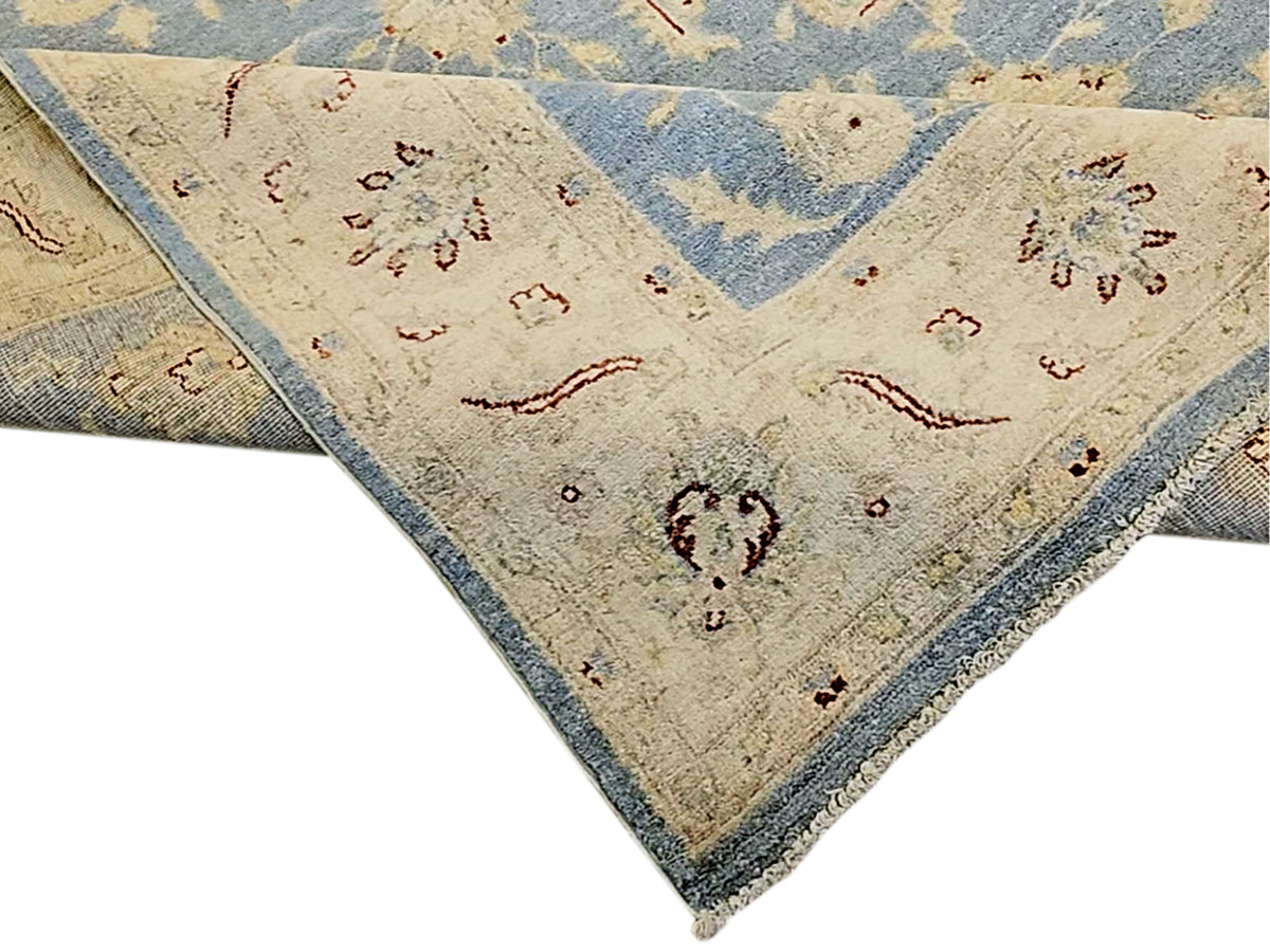 Afghan rug corner close-up with blue trim and cream field featuring floral medallions