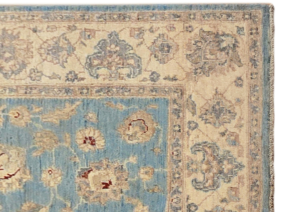 Close-up of light blue area rug with beige floral ornaments and border details