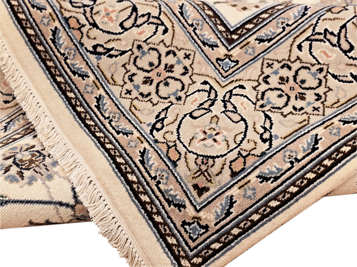 Nain rug corner detail with cream background, navy accents, floral vines, and short fringe