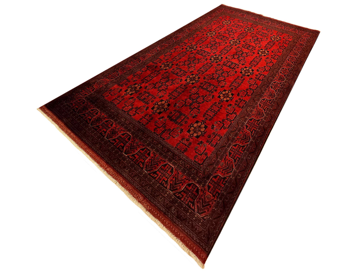 Red rectangular area rug with dark pattern medallion and tan fringe along sides.