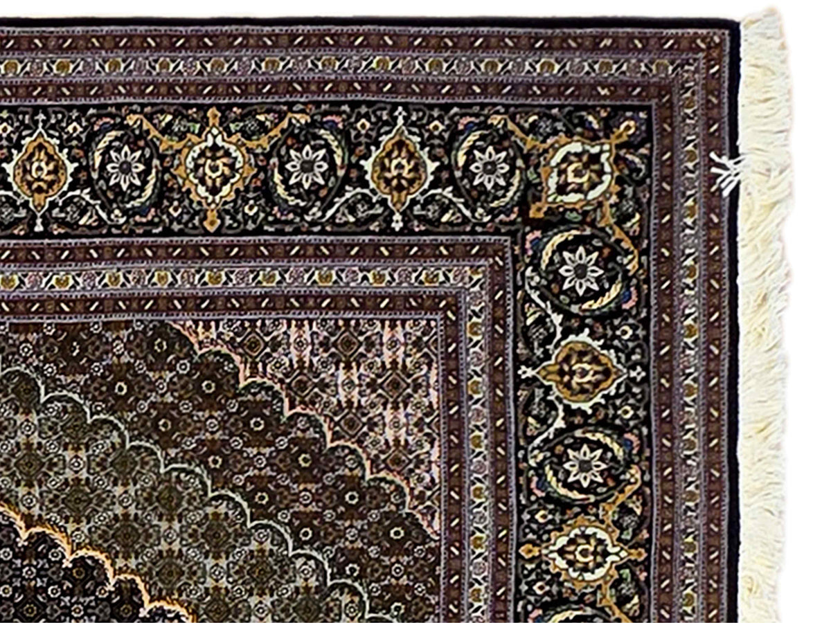 Close-up of dark rug border with gold floral motifs and white fringe
