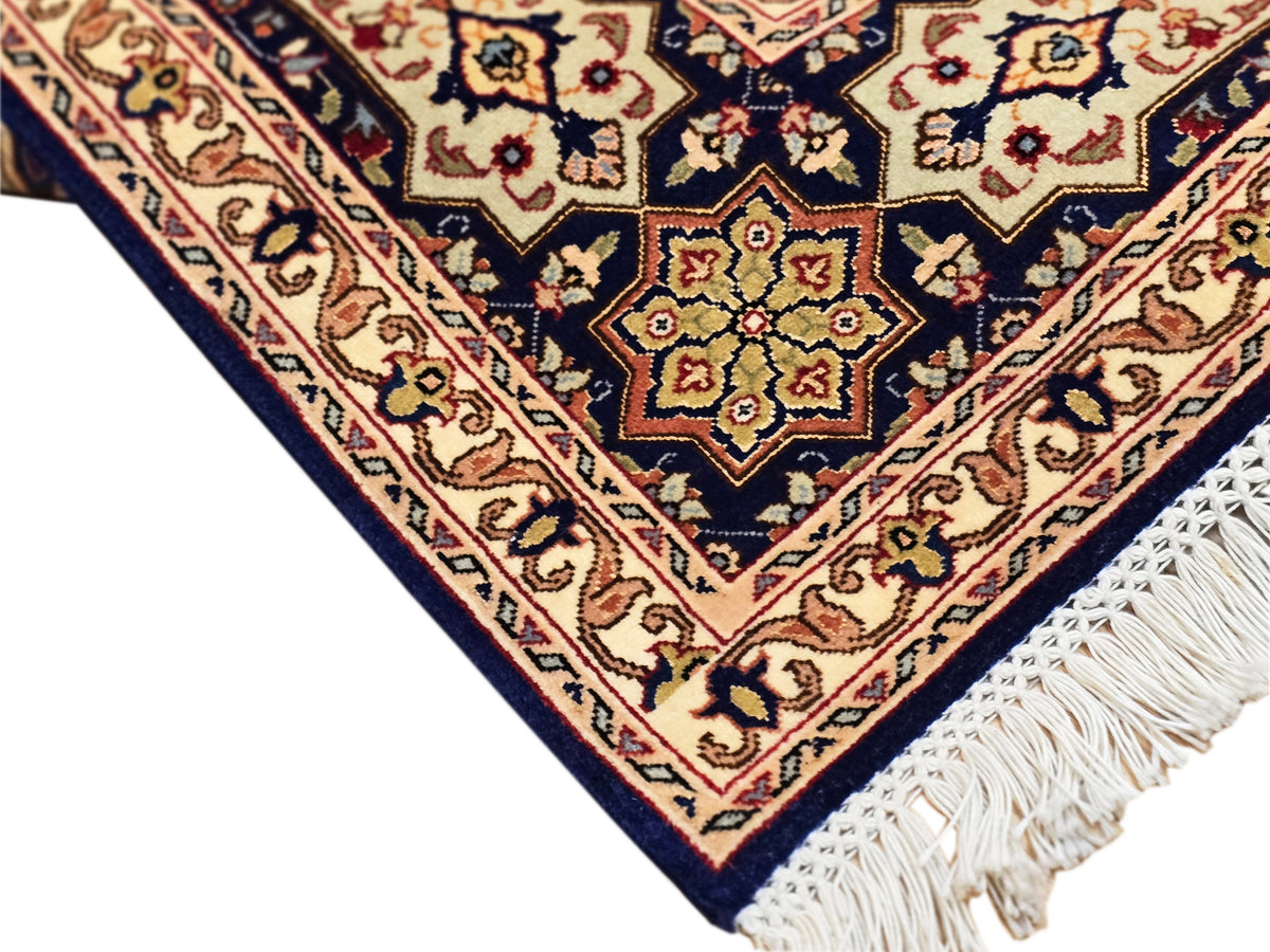 Close-up of rug corner with navy ground, cream outlines, and white fringe