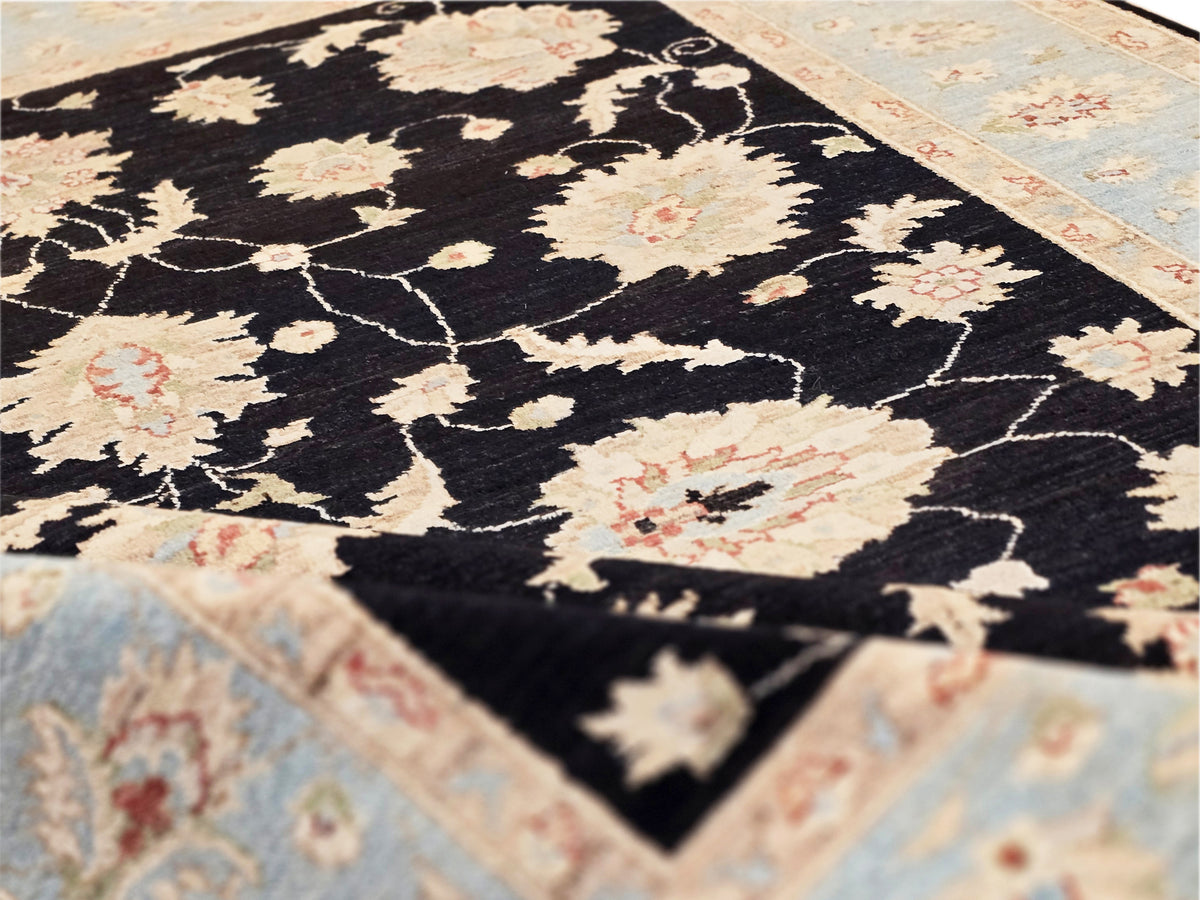 Close-up rug section: black background with cream and blush floral clusters and vines