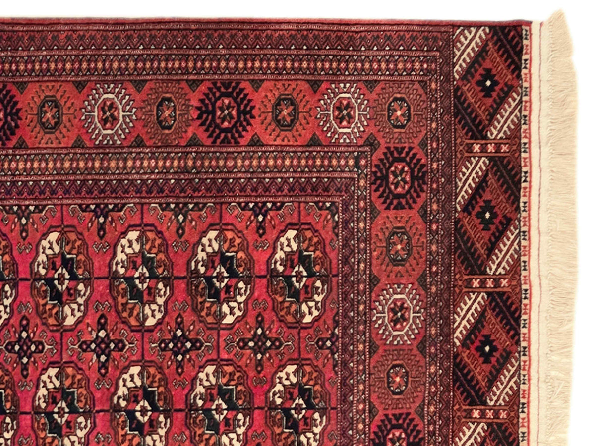 Red rug corner with repeating medallion motifs, black and ivory geometric details