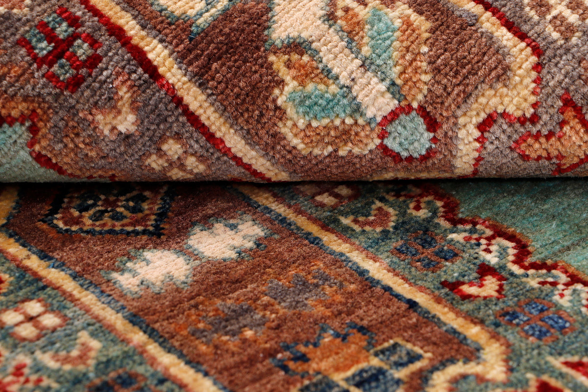 Turquoise rug close-up with multicolor geometric lines and frayed fringe edge