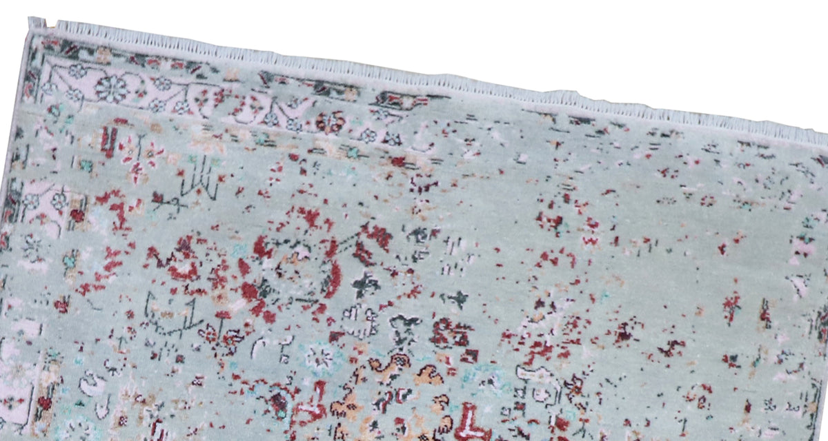 Oushak rug with light blue-gray base, red speckled floral pattern, and border fringe