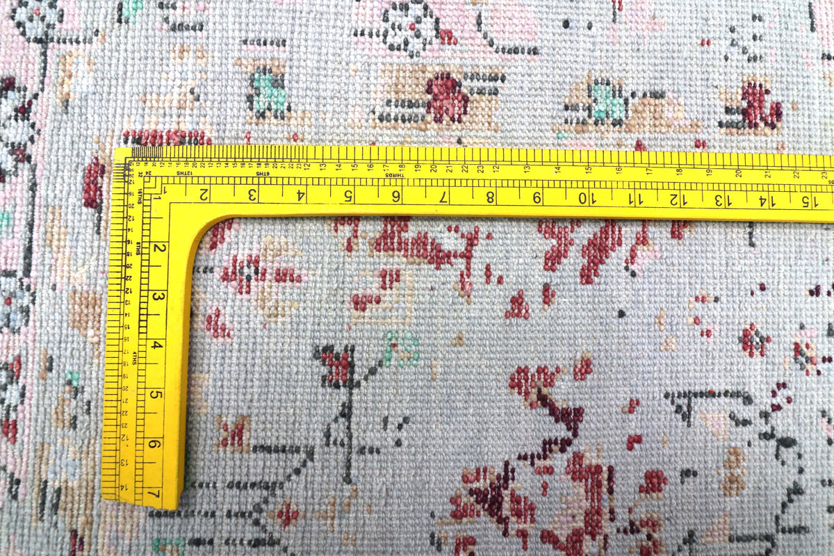 Oushak rug close-up with light blue-gray field, red speckles, and measuring tape across