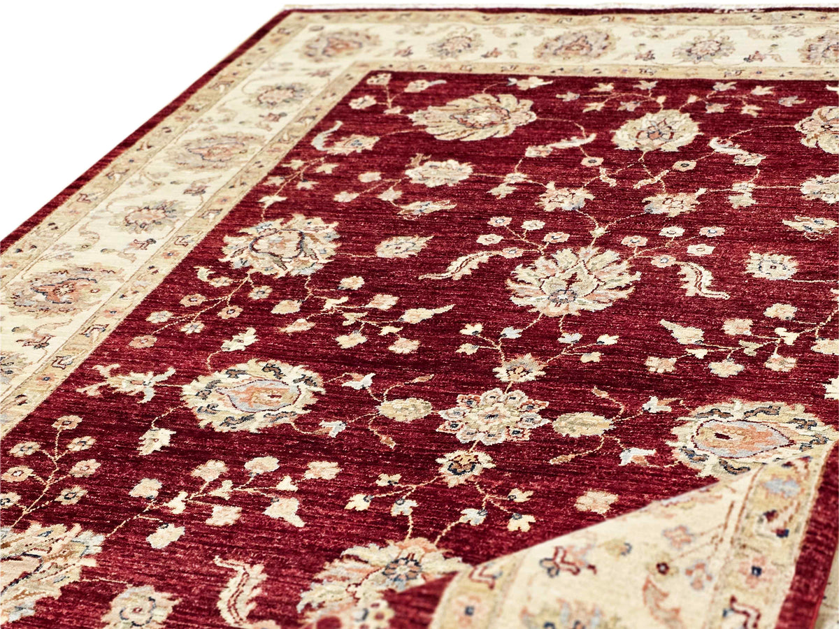 Diagonal close-up of red rug with cream floral sprays and ornate medallions