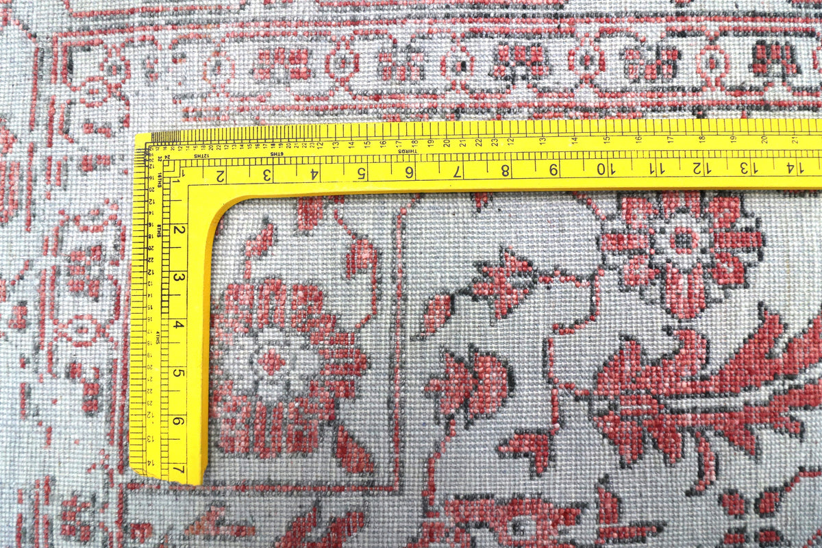 Rug close-up corner with red floral motifs and measuring tape along the edge