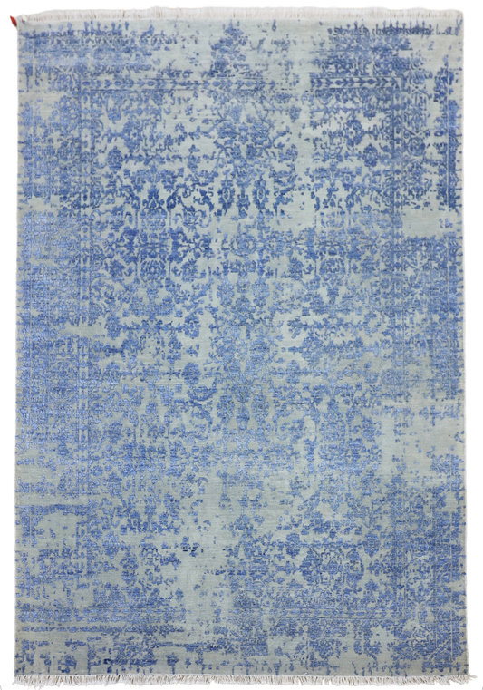Rectangular blue mist rug with distressed allover pattern and short fringed border, flat view.