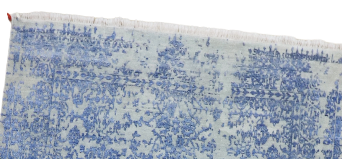 Blue mist rug close-up with distressed pattern and short fringed border along the top edge.
